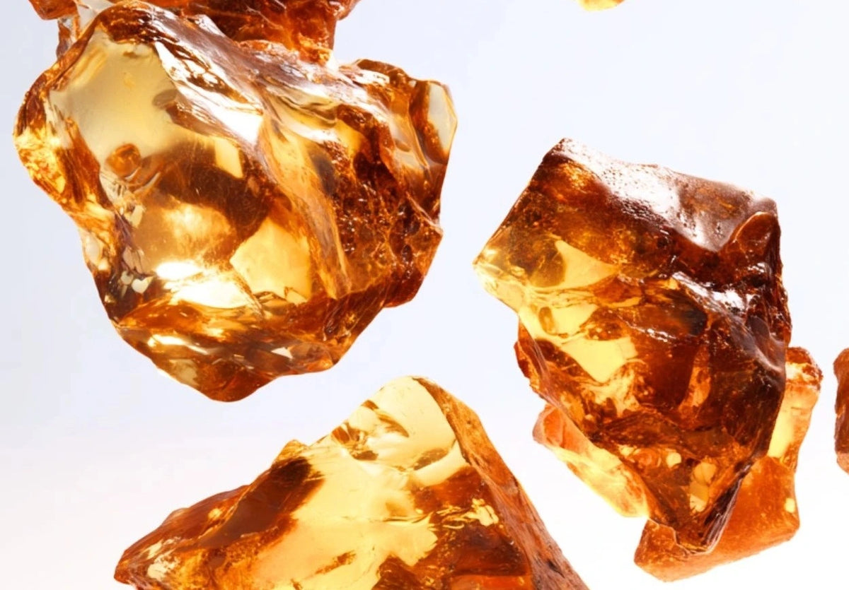 Several pieces of translucent, amber-colored resin floating against a bright white background.